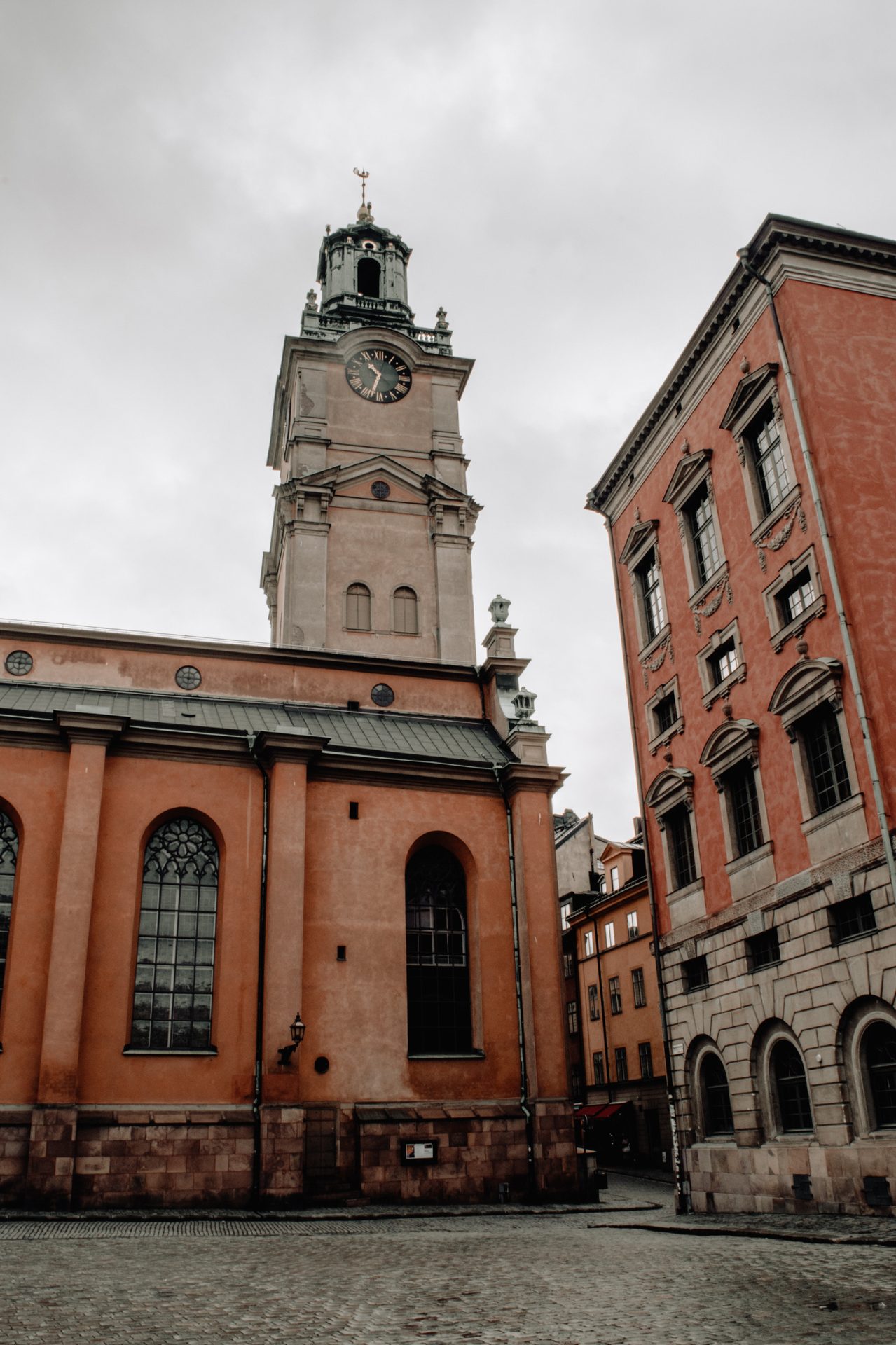 A church clock tower above a cobbled square in Stockholm